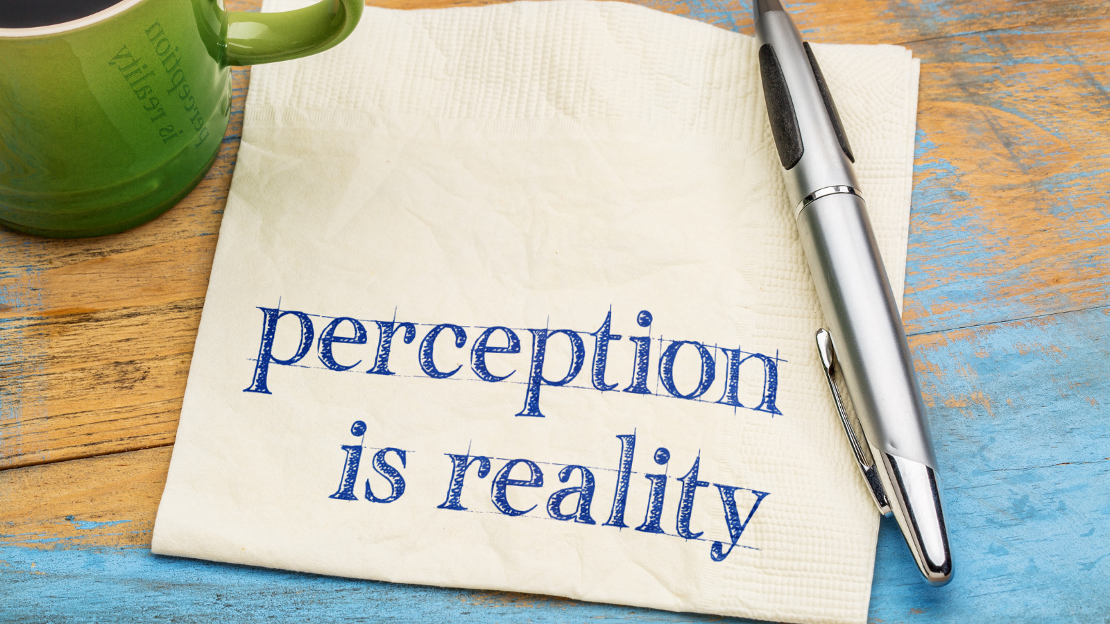The phrase Perception is reality written on a paper napkin.