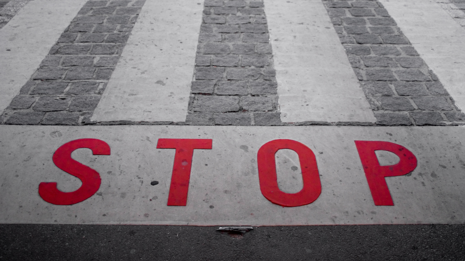 The word STOP painted at a crosswalk in red.