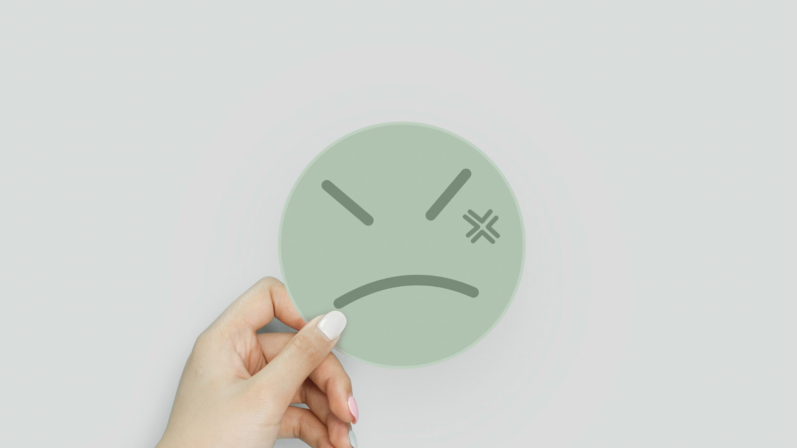 Hand holding up a card with an angry emoji on it.