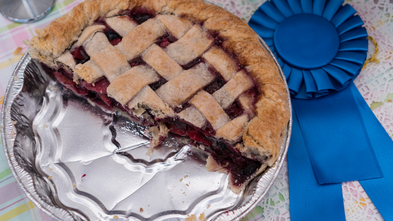 Half-eaten cherry pie next to a blue ribbon award.